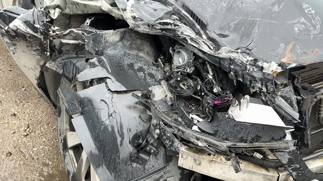 A car is severely damaged following a collision and road accident incident recently. This image features a detailed closeup of a car showing extensive frontend damage resulting from a serious accident