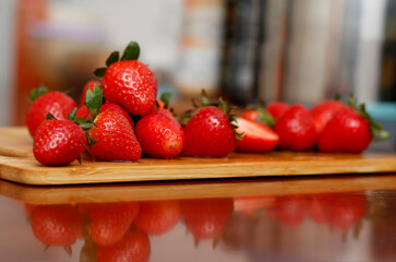 Fresh Ripe Red Strawberries on Wooden Cutting Board with Reflection on Table