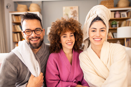 Multiethnic Group Of Friends Wearing Bathrobes And Hair Towel Relaxing During Home Spa Day In Living Room - Powered by Adobe