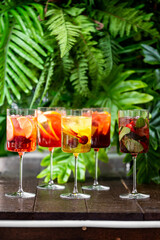 Five elegant cocktail glasses filled with colorful drinks, garnished with fresh fruits and herbs, set against vibrant tropical backdrop Refreshing summer beverages perfect for parties and celebrations