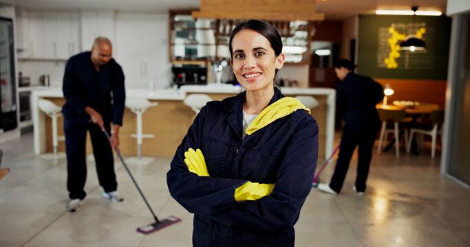 Woman, portrait and janitor with smile for maintenance job, hygiene and arms crossed with team in uniform. Pride, happy and cleaner with colleagues mop floors, overalls or confident at workplace