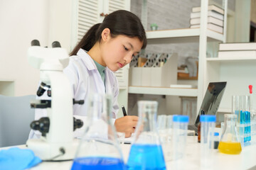 Student attentively records experimental data in a science lab, maintaining focus while monitoring...