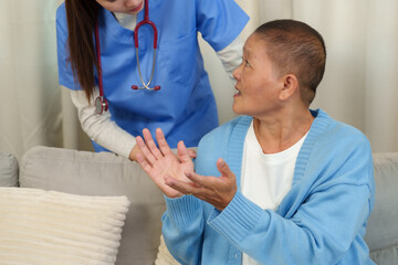 Physiotherapist attentively observes elderly patient explaining hand symptoms, providing a calm and...