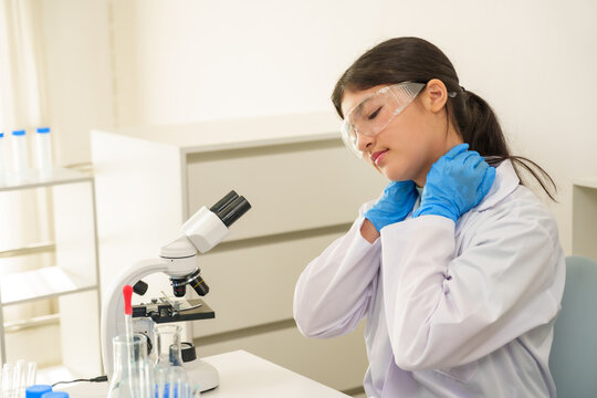 Asian teenage girl adjusts gloves and lab coat in science lab, preparing to resume classroom experiment, showing readiness and commitment to scientific learning. - Powered by Adobe