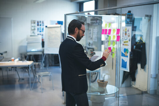 Multicolored sticky notes forming grid on transparent glass partition in modern office, copy space