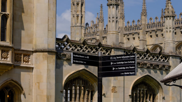 Black directional signs indicating distances to Fitzwilliam Museum, The Backs and River, Tourist Information Centre, Cambridge Corn Exchange, Cambridge Arts Theatre and Market Square in Cambridge, UK