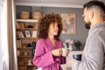 Happy Couple in Bathrobes Sharing Morning Coffee and Conversation Indoors