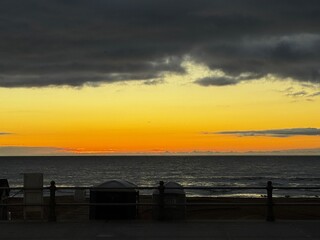 Oceanfront sunrise from Virginia Beach boardwalk with cloudy sky and vibrant yellow horizon