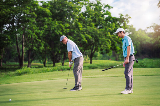 Senior Man Teaching Young Golfer on Green Lawn During Outdoor Golf Lesson for Family Bonding and Sport Education