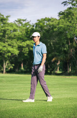 Young Asian Golfer Walking on Fairway After Tee Shot in Natural Green Golf Course on a Bright and Relaxing Summer Day