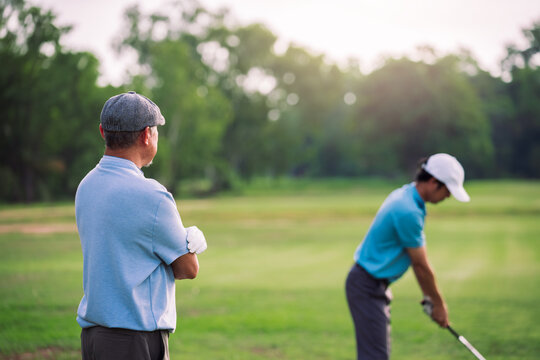 Senior Man Teaching Young Golfer on Green Lawn During Outdoor Golf Lesson for Family Bonding and Sport Education