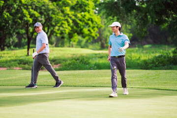 Fototapeta premium Happy family bonding moment between senior and young golfer during relaxing round of golf. Shared laughter, teamwork, and connection in nature.