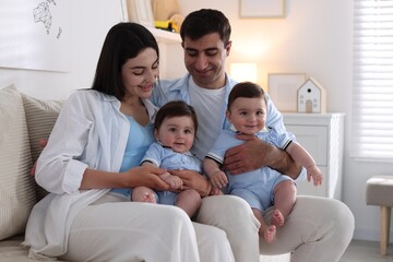 Fototapeta premium Happy family. Parents with their twin babies on sofa at home