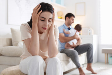 Woman suffering from postpartum depression and her husband with baby at home, selective focus