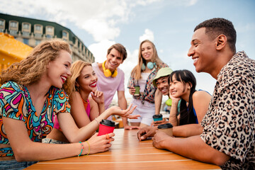 Diverse group of young friends enjoying a summer day together, bonding over coffee and sharing laughter outdoors
