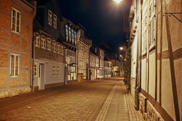 Quiet medieval street lined with timber-framed houses illuminated by warm night lighting in a historic German town.