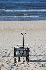 Foldable transport trolley dark color on the sandy Baltic coast