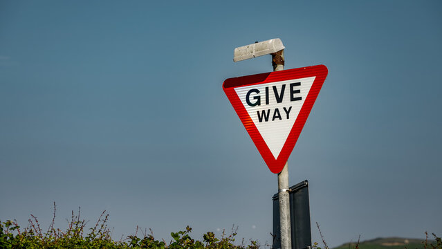 Red and white triangular give way sign against blue sky in Whitby, North York Moors National Park, UK