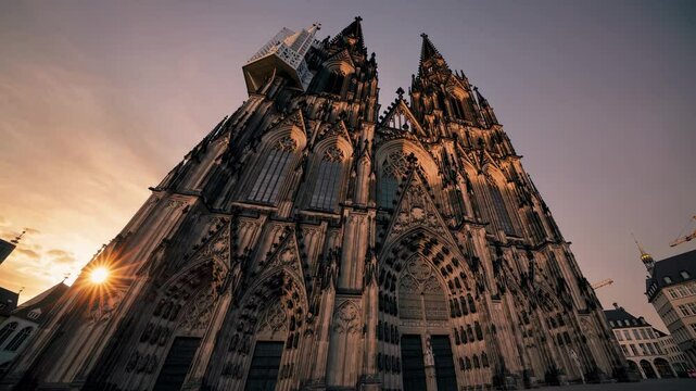 Gothic cathedral facade at sunset with intricate stonework and towering spires, dramatic upward angle, ideal for architecture photography, historical tourism, and European travel visuals