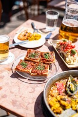 Tapas and beer on sunlit restaurant table