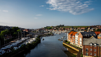 River Esk flowing through Whitby harbor with sailboats and St. Mary's Church in the background, North York Moors National Park, Whitby, England