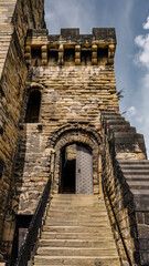 Low angle view of stone steps leading to an old wooden door in Newcastle Castle, UK, with a cloudy sky above
