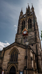 The imposing Newcastle Cathedral stands tall against a backdrop of clouds, its clock tower a prominent feature in the cityscape