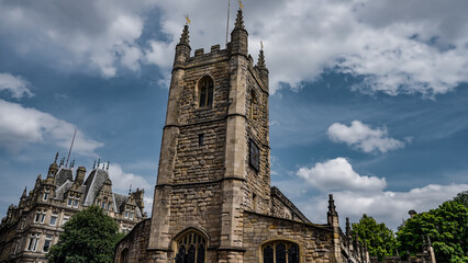 St. Nicholas Cathedral's stone tower standing tall against a backdrop of dynamic clouds in Newcastle upon Tyne, UK