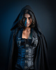  portrait of mysterious hooded woman in black cloak,  gothic fantasy or dystopian character. posing with gestural magical hand poses.  lit with moody shadows, studio scene on dark isolated background