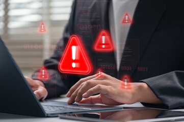 Cybersecurity alert warning displayed on laptop screen while businessman types during work. corporate hacking threat, cyberattack, data breach and malware threat in professional setting,