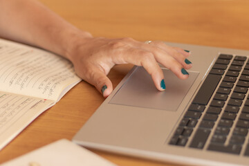 Hand Using a Laptop Trackpad with a Notebook Nearby
