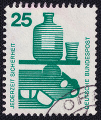 A bottle of alcohol, a glass and an overturned car on a 1971 Germany vintage postage stamp....