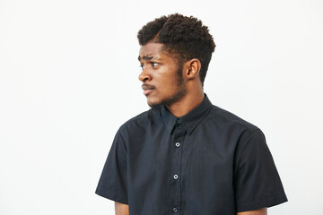 Black man posing thoughtfully in a stylish black shirt against a neutral background, conveying a...