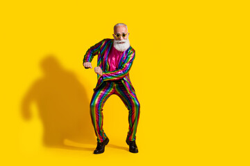 Eccentric elderly man in funky striped suit dancing against vibrant yellow background