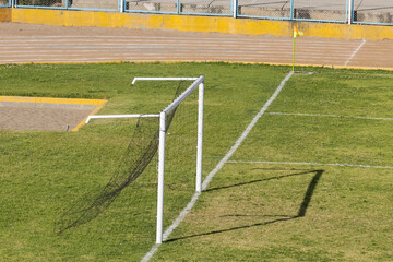 Soccer field with goal and goal post with roll-up netting on natural green grass, with goal line...