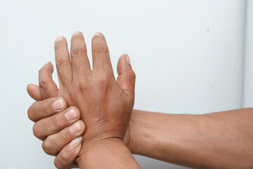 Fototapeta premium A man uses his other hand to feel pain and tingling, along with Guillain-Barré syndrome and numbness in his hand. An elderly man tries to massage himself to relieve the pain in his wrist.