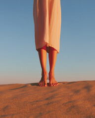 Bare feet standing on warm sand at sunset with soft light and minimalist background