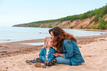 A young mother with her three-year-old daughter on an evening beach, a mother-daughter relationship