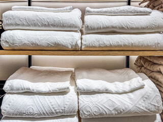 Neatly arranged white towels displayed on wooden shelves inside a modern home goods store