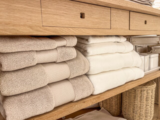 Soft and neatly organized towels stacked on wooden shelf in a serene bathroom setting