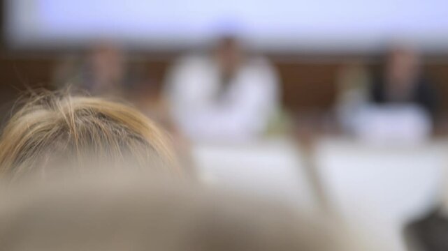 Woman with long brown hair is looking at something. The image is blurry and the woman's face is not visible