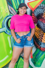 Smiling Latina Woman in Casual Outfit by Colorful Graffiti