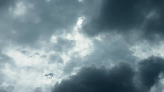 Dramatic dark storm clouds gathering in the sky before a thunderstorm with patches of bright light breaking through.