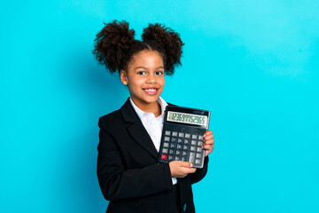 Confident young student holding a large calculator in a formal suit against a bright turquoise...