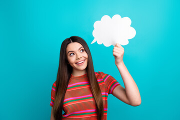 Young woman holding a speech bubble on vibrant turquoise background, standing happily and...