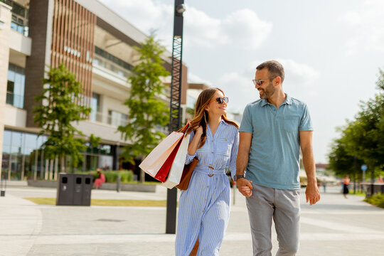 Couple enjoying a sunny day strolling through a vibrant shopping district with colorful storefronts and lush greenery