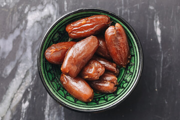 Dried dates in bowl. Brown sweet fruit. Healthy vegan snack. Natural energy source. Organic clean food.