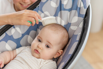 Brushing baby’s hair in modern rocker.