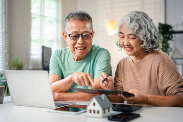 Asian Senior Couple Planning Retirement Finances with Tablet and Laptop for Future Investments and Estate Goals at Home for Financial Security, Savings, and Investment Planning