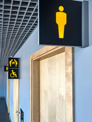 Signs indicating men's restroom and accessible facilities in a modern public building hallway